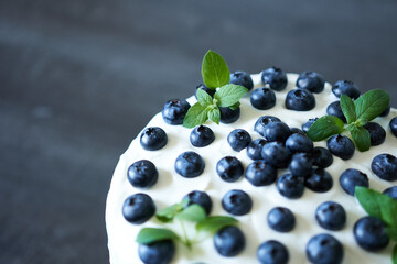 Meringue cake with fresh blueberries and mint on black background