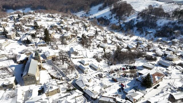 Snow-covered rooftops and winding streets of Nymfaio village nestled in the mountains during winter. Greece