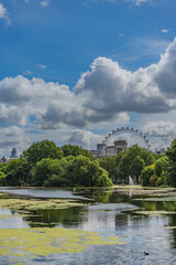 A tranquil pond in Public Park with lush greenery in the foreground, while the Iconic landmark and surrounding buildings are visible in the background.