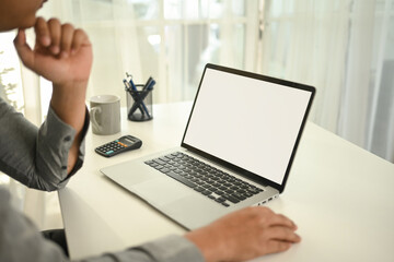 A close-up of a professional businessman sits at a desk, staring at a blank laptop screen. A calculator, pen holder, and coffee mug are nearby