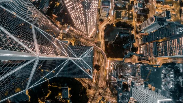 4k still video of Hong Kong's aerial cityscape at night, zoomed in on illuminated skyscrapers and intricate road systems.