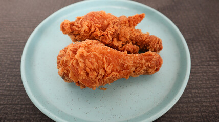 crispy kentucky fried chicken in a blue plate on black background, selective focus