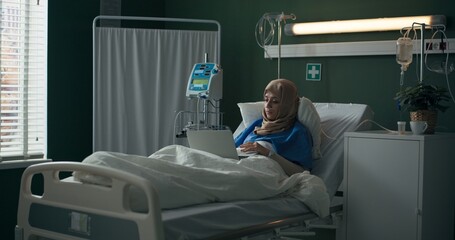 Arab woman working from a hospital bed.