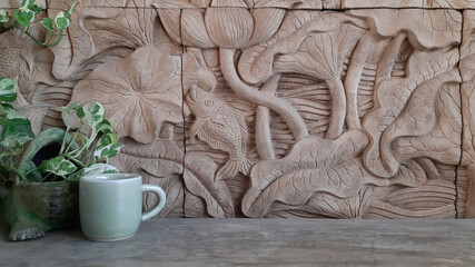 A speckled betel pot and a jade green coffee cup on a bare cement seat with a lotus-pattern stone...