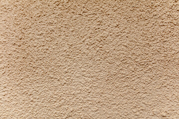 A wall with a beige color and a rough texture