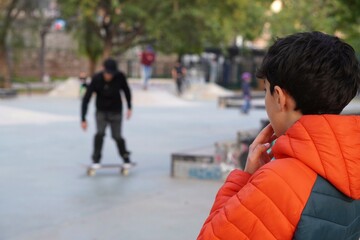 child watching with interest the skaters at a kate park before learning to skate himself