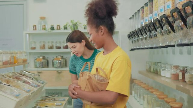 Female customer fills cereal foods in a glass jar, lever the reusable container on refill store shelves, zero-waste and plastic-free grocery, environment-friendly, sustainable lifestyles.