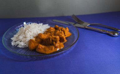 Delicious chicken curry served with fluffy white rice on a blue background