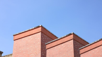 Red brick apartment building with sky, Shapes and simplicity of architecture, Fragment of roof of modern private dwelling house against of sky, Blue sky and Sunlight in background with copy space.