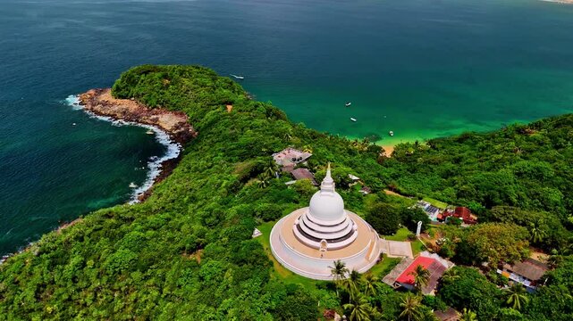 Aerial of Buddhist temple Japanese Peace Pagoda, coastline and trees, Rumassala, Sri Lanka
