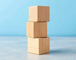 Stacking blank Three light wood blocks arranged in ascending size on a blue surface.