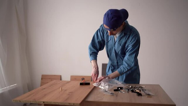 a repairman assembler of furniture assembling and installing a new cabinet in the interior of a house uses a hammer and wooden dowels