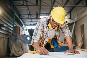 Carpenter sketching table plans on wood at a working desk. builders and engineers designing...