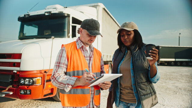 Warm moment of African American female truck driver enjoying her warm drink while talking to inspector or manager. Man in reflective vest asking questions about lorry. Mechanical inspection. - Powered by Adobe