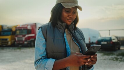 Camera focus on African American woman using smartphone with both hands. Typing on screen with...
