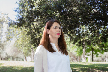 Middle-aged woman in a natural environment, dressed in neutral tones. Concept of serenity, balance and connection with nature