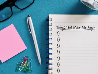 Notebook listing things that make me angry on turquoise desk