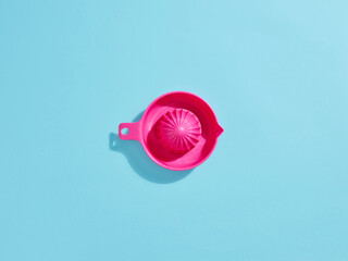 Pink citrus juicer creating fresh juice on vibrant blue background