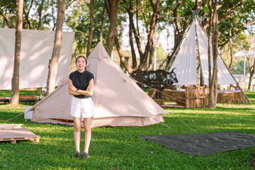 Young asian woman entrepreneur managing a glamping tent resort is smiling with crossed arms in the...