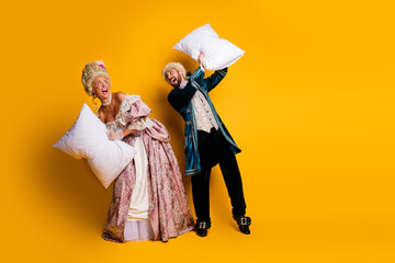 Playful Couple in Retro Costumes Having Fun Against Yellow Background