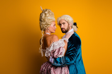Elegant Couple in Vintage Costumes Posing Against Yellow Background in Historic Renaissance Style