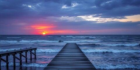 Obraz premium Orange sunset over Gulf of Mexico with sun setting inside wooden jetty framing, birds flying over dark blue ocean waves, Florida, pier, birds