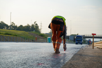 Construction Worker Marking Fresh Asphalt with Spray Can on Highway