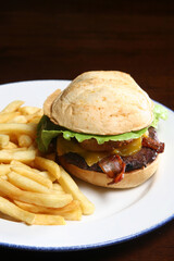Gourmet cheeseburger featuring crispy bacon, golden fries, and crunchy onion rings