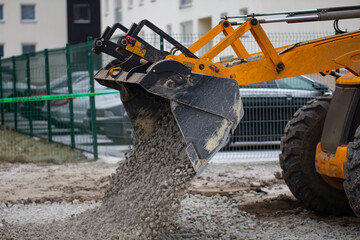Industrial front loader excavator bucket side view of exposing gravel to road construction object. 