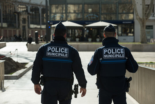 Fototapeta Narbonne - France - 11 february 2025 - Portrait on back view of two policemen patrolling in the street
