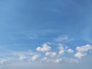 Obraz premium Clear blue sky with a few clouds. The sky is very bright and the clouds are scattered throughout. Natural background texture 