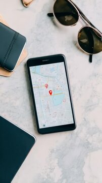 Navigation map app showing route on smartphone screen near sunglasses and notebook, tracking travel destination using digital geolocation technology
