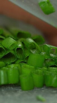 Close up of hands cut fresh green onions with kitchen knife. Cooking food with greens. Greens, vegetables. Vertical shot