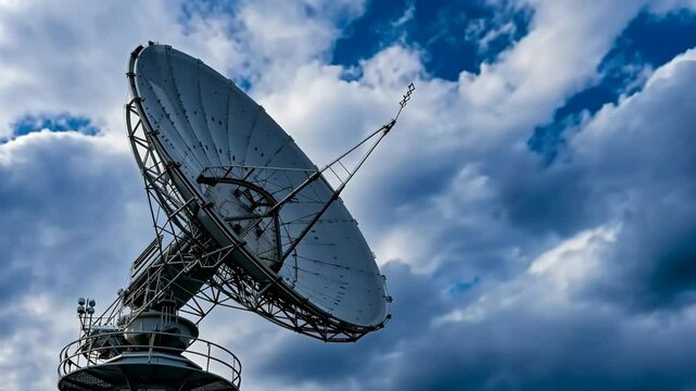 A satellite dish is pointed towards the sky. The sky is cloudy and the sun is not visible