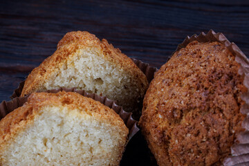 Cut and whole cupcake on dark wooden background.
