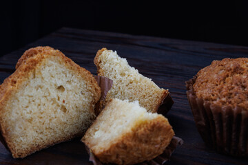 Cut and whole cupcake on dark wooden background.