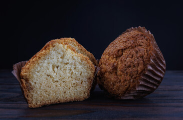Cut and whole cupcake on dark wooden background.