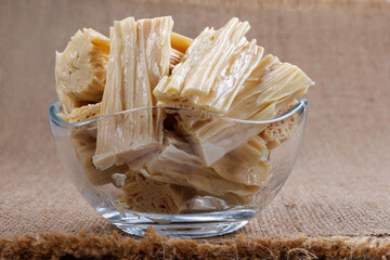 Fuzhu in a glass cup on a burlap napkin, side view. Yuba in a cup close-up.