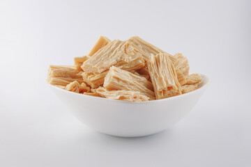Fuju soy sticks in a white plate on a white background. Yuba side view.