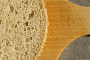 Close-up of bread texture with porous structure on a wooden cutting board.







