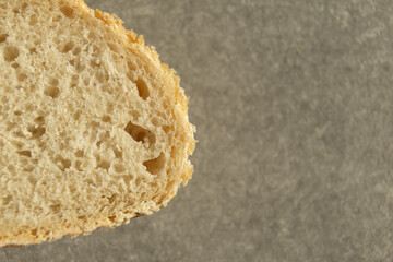 Close-up of bread texture with porous structure on a gray surface.