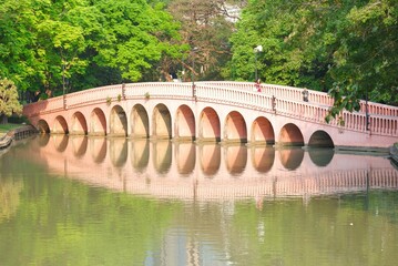 A beautiful bridge across the lake at Jatujak public park,Thailand with green trees background 