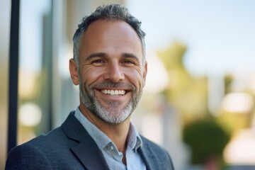 Obraz premium Smiling bearded man with goatee, beard, and mustache. Wearing a suit and blue shirt. Poses for portrait photo.