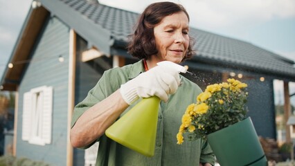 Charming Caucasian woman in green shirt and red necklace holding small bush with yellow flowers....