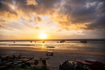 Serene beach sunset with boats and dramatic clouds.