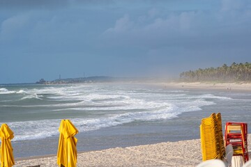 Serene beach scene with yellow umbrellas and waves.