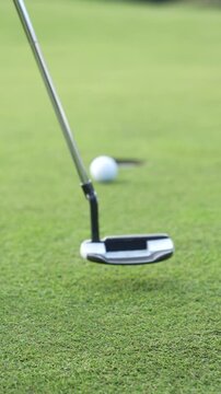 A golf ball is on a green grass field ready for the putt.