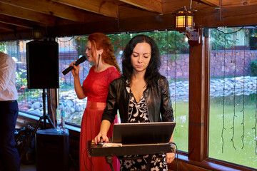 Host of a wedding ceremony with a musical assistant DJ. Young women