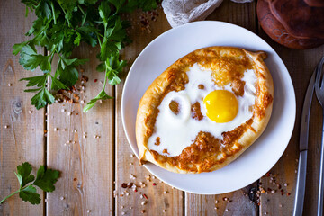 Khachapuri with egg for breakfast on a wooden table. Home cooking: classic khachapuri for lunch. Georgian flatbread. View from above. close-up.