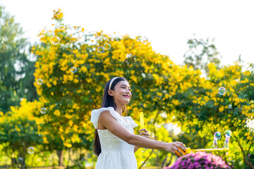 Fototapeta premium Asian Woman Blowing Bubbles in a Park